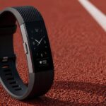 Persona indossa un fitness tracker mentre si prepara a correre in un parco.