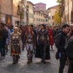 Appassionati di fumetti, videogiochi e cosplay attraversano una strada del centro storico di Lucca durante un festival dedicato alla cultura pop.